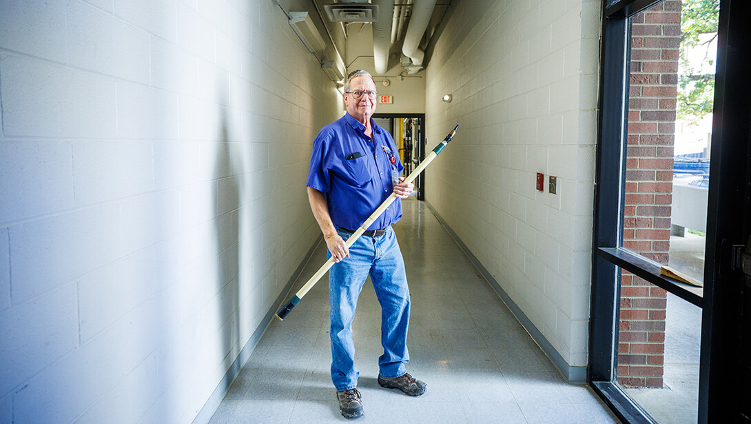 Duane Grosse poses for a photo in Hamilton Hall with his modified paint stick.