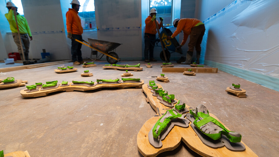 Employees from Stephens & Smith Construction pour wheelbarrows of cement around a 3D printed replica of an incomplete Menoceras arikarense fossil – a small, extinct rhinoceros found in Nebraska fossil beds. The replica was printed by Frontier Tech Lab at the Nebraska Innovation Studios and will be part of a new fossil dig in the redesigned Marx Science Discovery Center in Morrill Hall.