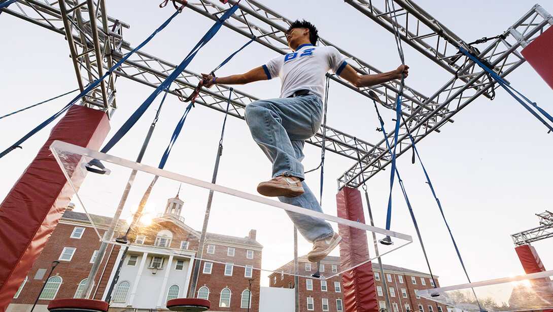 Josh Ronquillo, a sophomore biochemistry major, maneuvers through the Ninja Challenge course to try and get a good time on the green space across from the Willa Cather Dining Complex.