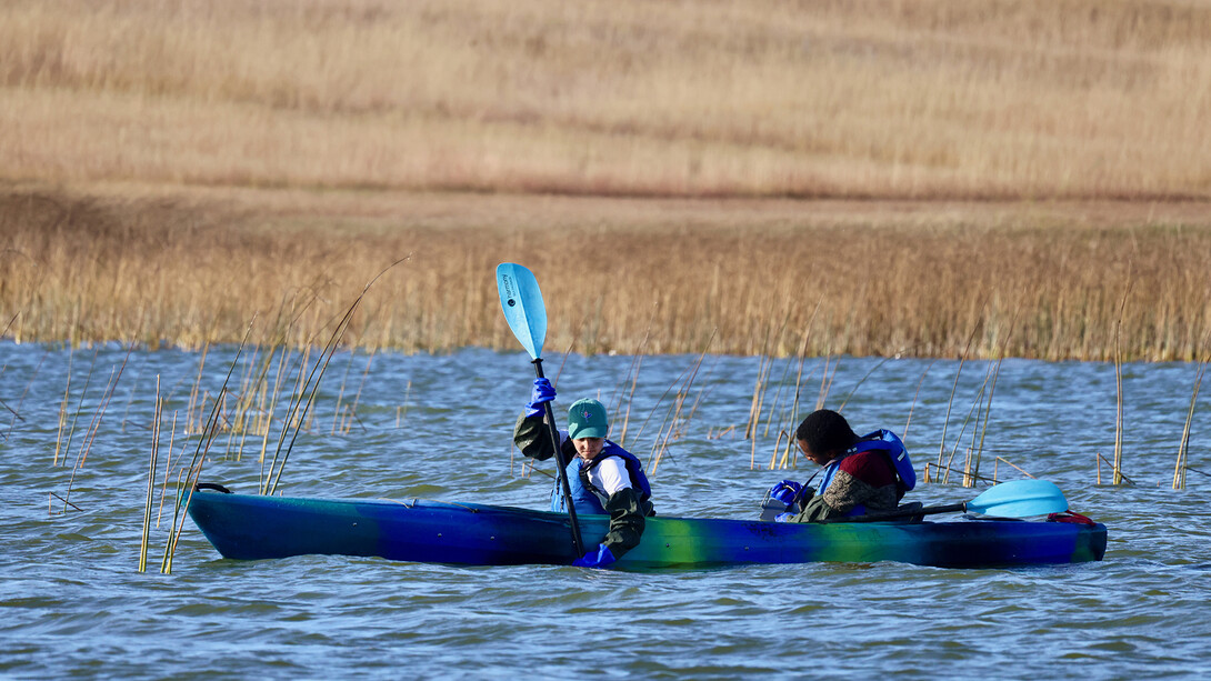 Student researchers (from left) Natalia Madrid and David Sirengo gather samples while in a canoe on a lake in the Sandhills.