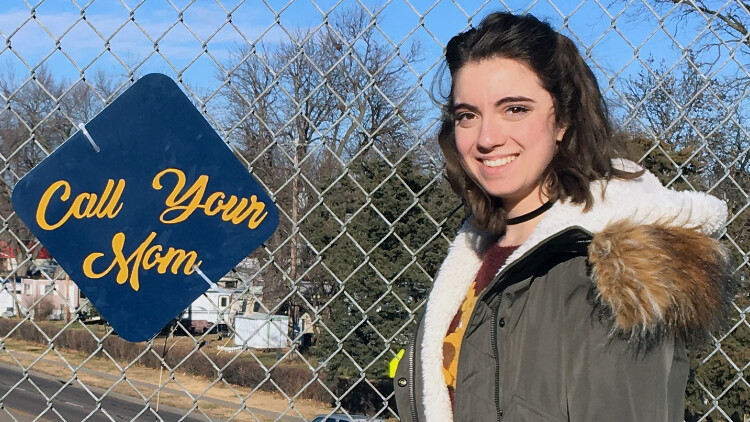 Anna Krause, a freshman history major, designed a sign that reminds people to call home. Students in the street art honors seminar posted their positive street art signs on fences throughout the Lincoln community on Dec. 5.