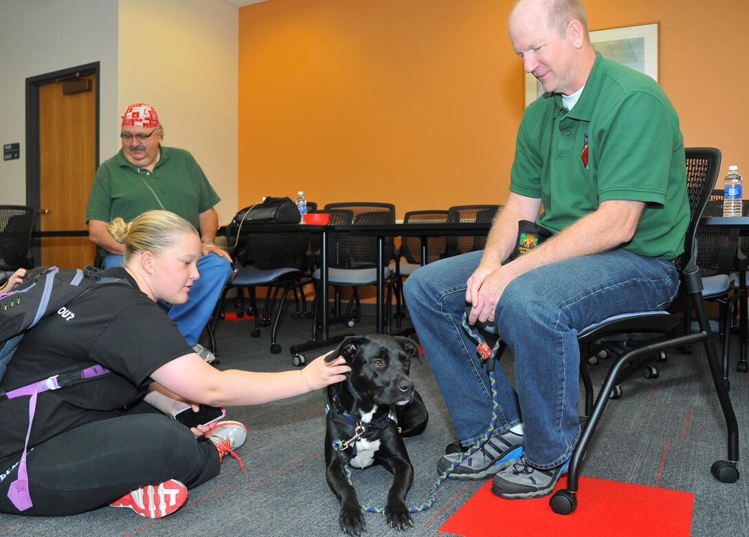 Amanda Stocking, a sophomore from California, visits Tide, a boxer/labrador mix, during the Oct. 15 Healing Hearts Therapy Dog visit to Love Library. Tide is owned by Randy Farmer (at right).