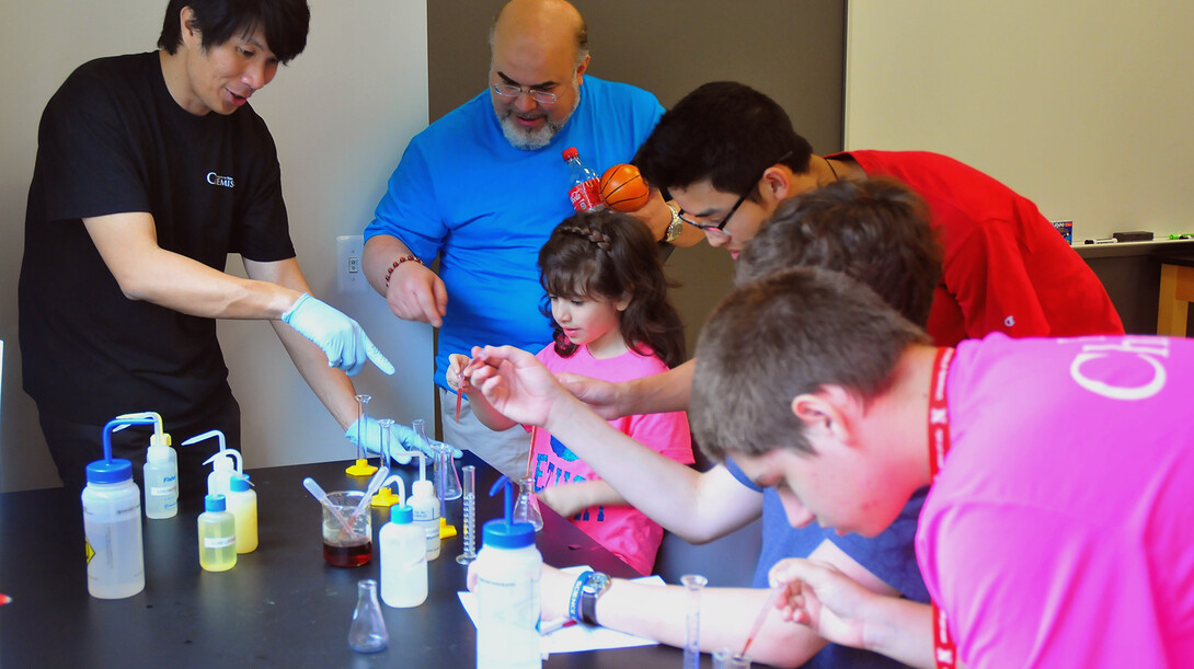 Jon Velasco (left), a graduate student in chemistry, guides Science Olympiad participants through an experiment that measures vitamin C in various drinks.