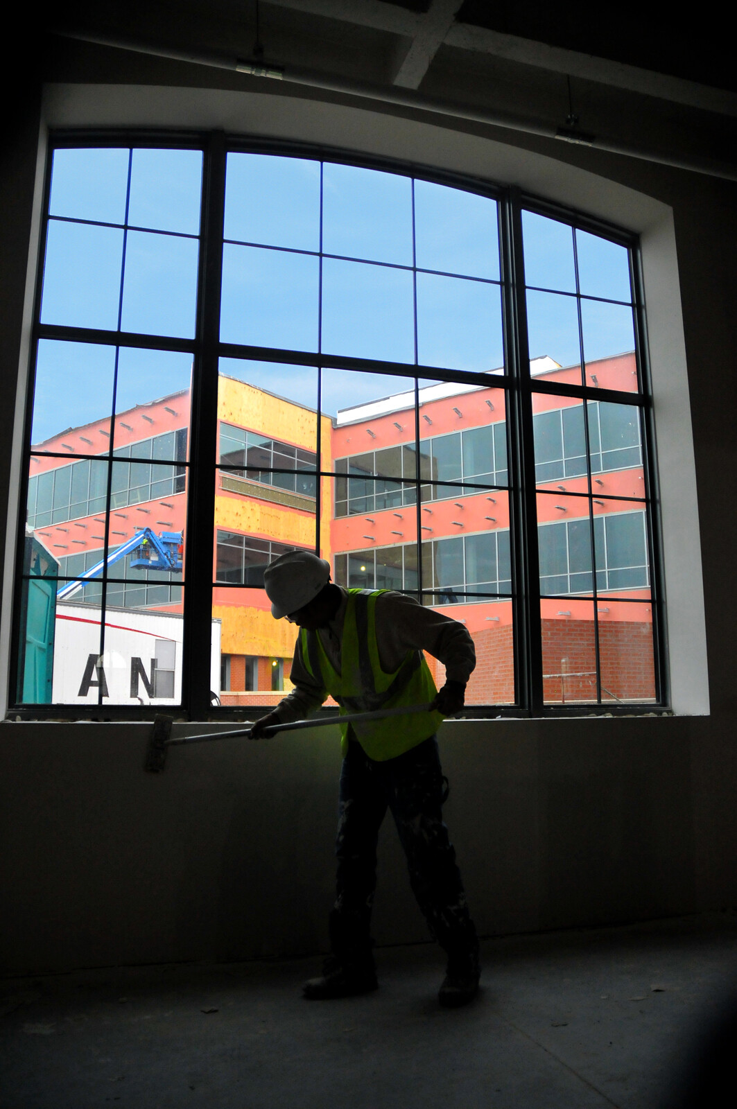 A construction worker sands a wall inside the 4-H Building. Pictured in the window is the Companion Building.