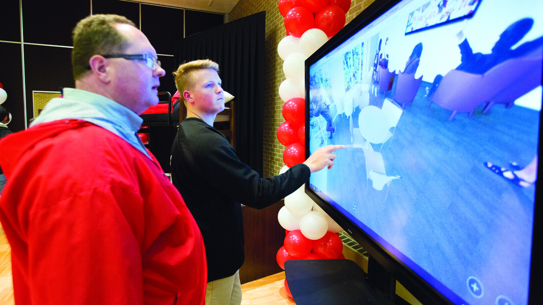 Todd (left) and Josh Seifert examine an interactive, 360-degree view of the university's new East Campus residence hall during a Nov. 17 open house at the East Union.