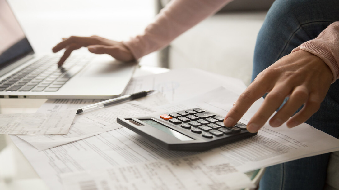 A person using a calculator next to a laptop and paperwork.