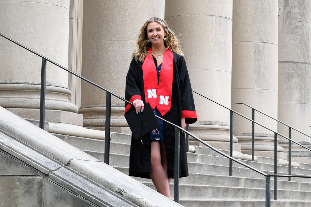 Emily Stratmoen in graduation gown on university steps