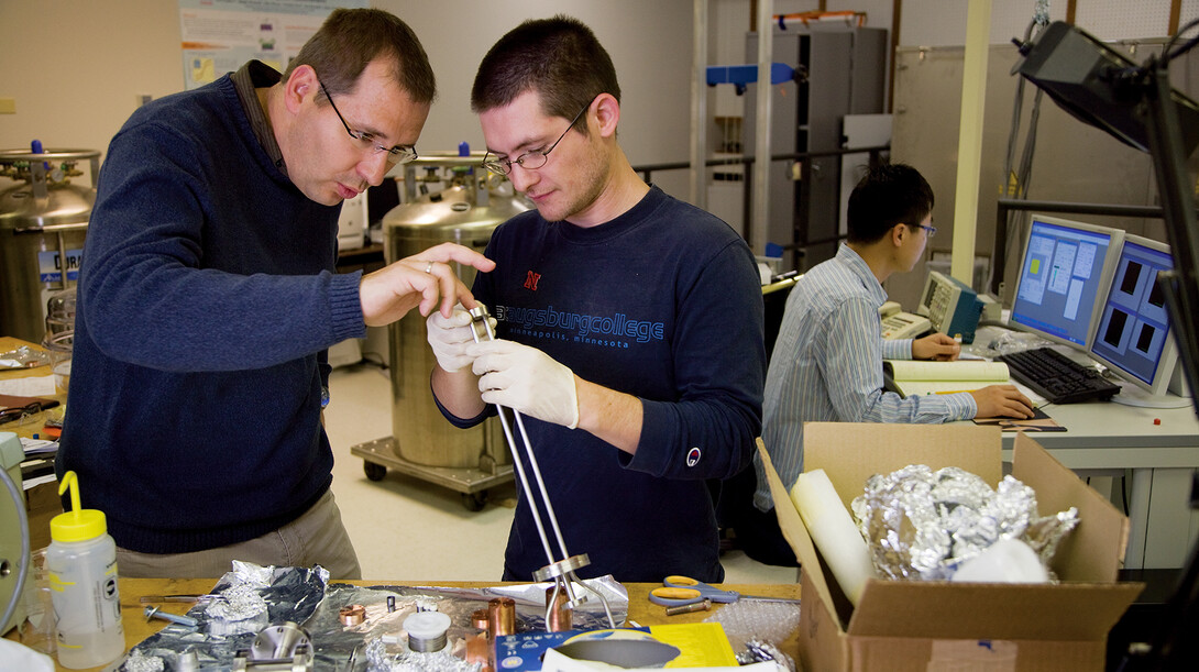 Axel Enders, associate professor of physics and astronomy, works with a graduate student in a campus research lab.