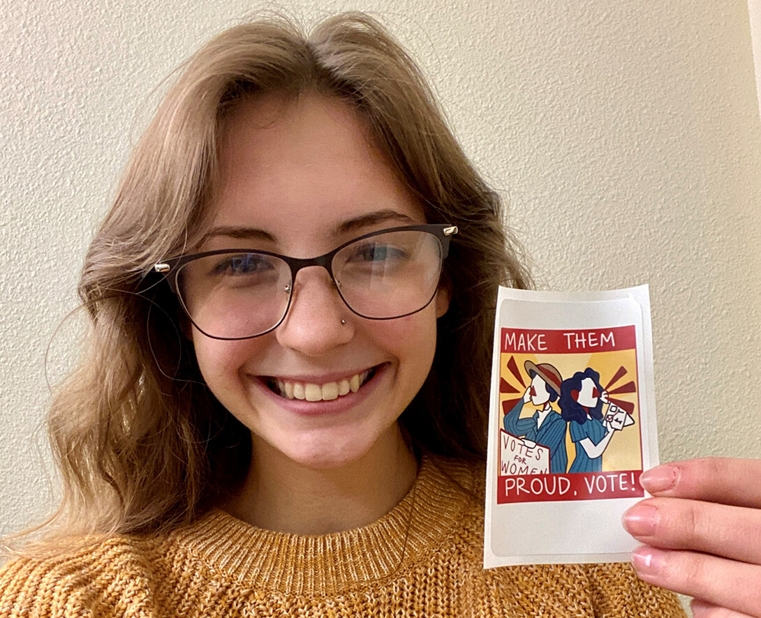 Maggie Scott holds the sticker created through the University Honors course led by Sandra Williams.