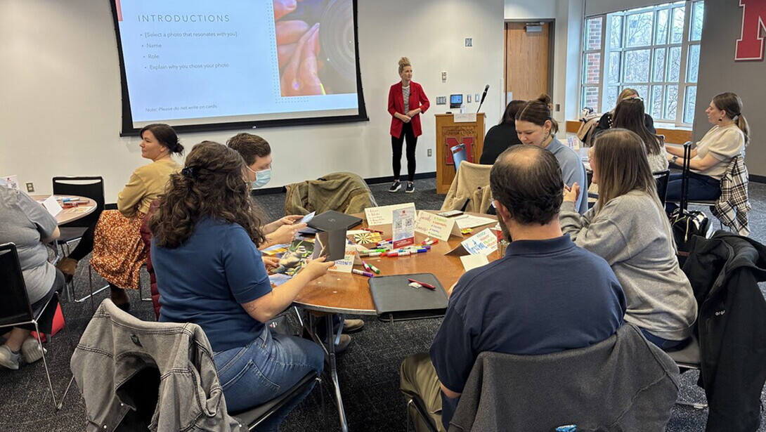 A woman stands in front of a seated group of people as she presents a workshop.