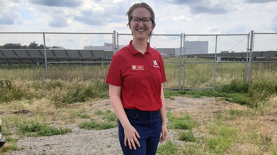 Energy intern stands next to solar panels