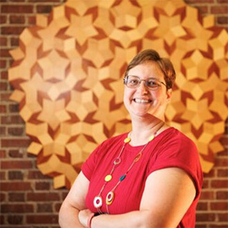 Wendy Smith standing next to a star sculpture hanging on a red brick wall.