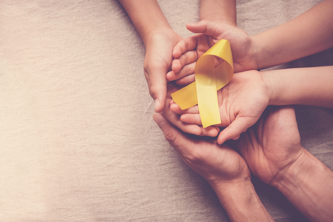 A yellow suicide awareness ribbon is held in enjoined hands