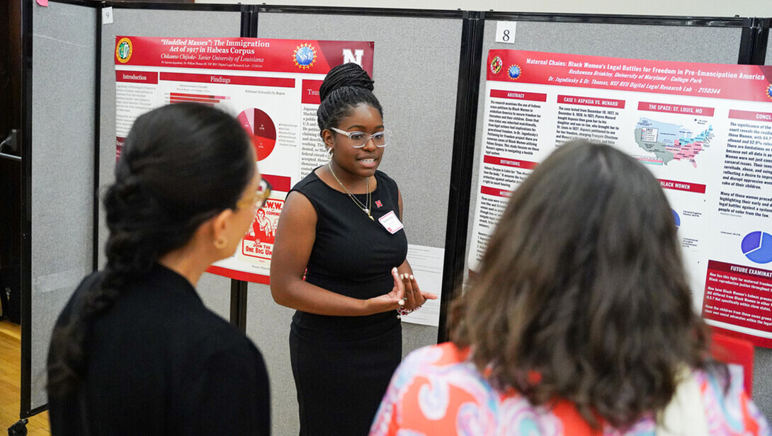 A student presents research during a poster session.