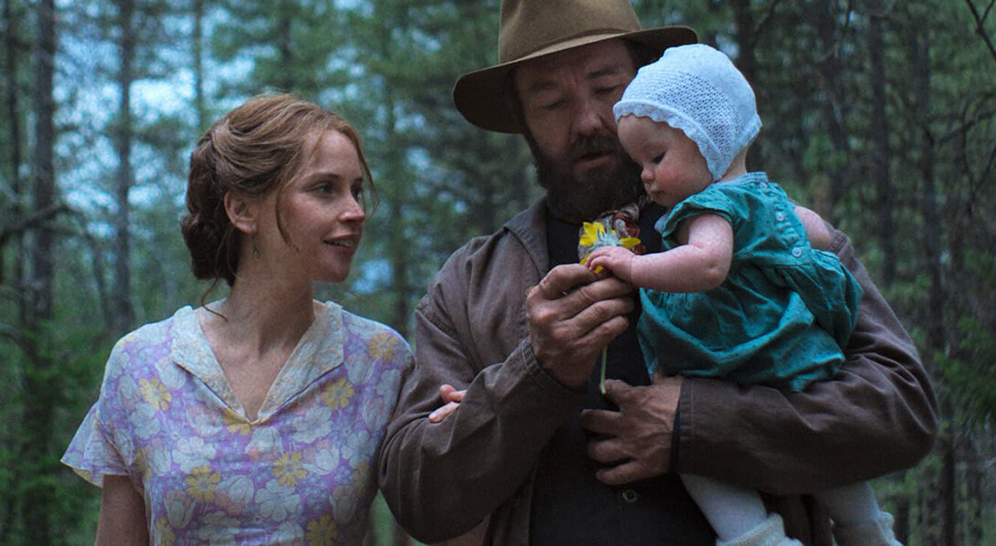 Felicity Jones and Joel Edgerton walk in a forest in "Train Dreams."
