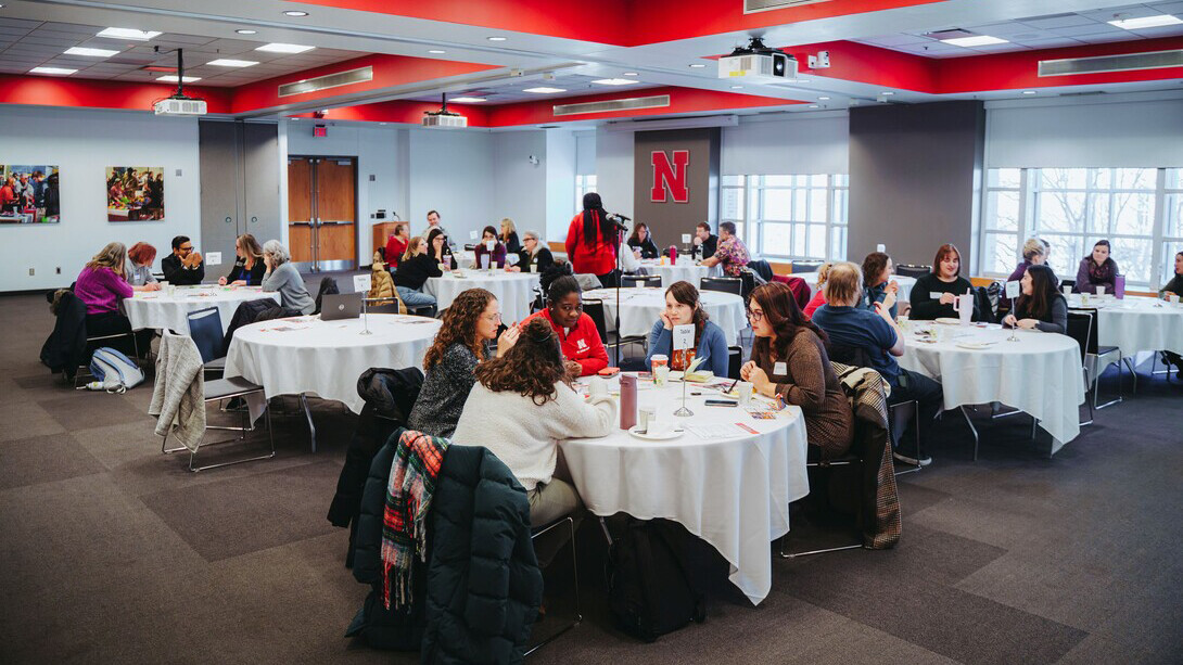 People sitting at tables in a Nebraska Union conference room.
