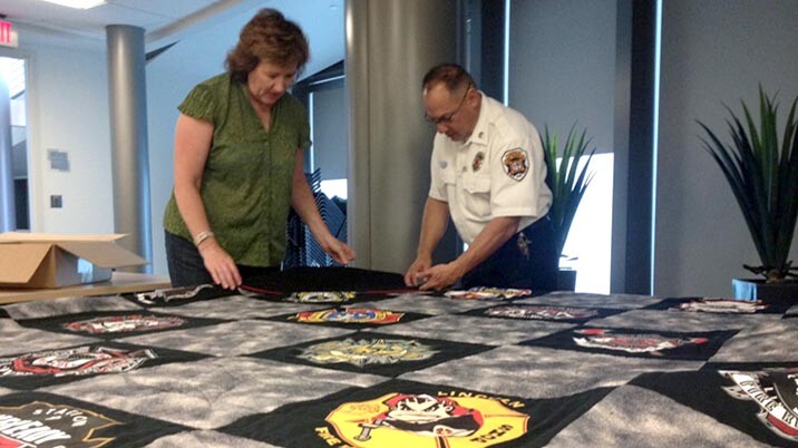 Carolyn Ducey, curator of collections at the International Quilt Study Center and Museum, and fire inspector Rick Campos examine the Lincoln Fire and Rescue T-shirt quilt that will be revealed during First Friday events on Nov. 6.