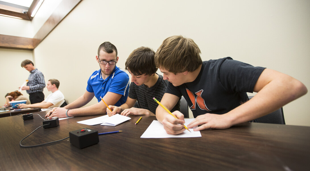 Tucker Merz, Justin Ernst and Preston Deckinger of Falls City High School ponder a math question posed by UNL's Mark Walker as they take on a team from Seward High School.