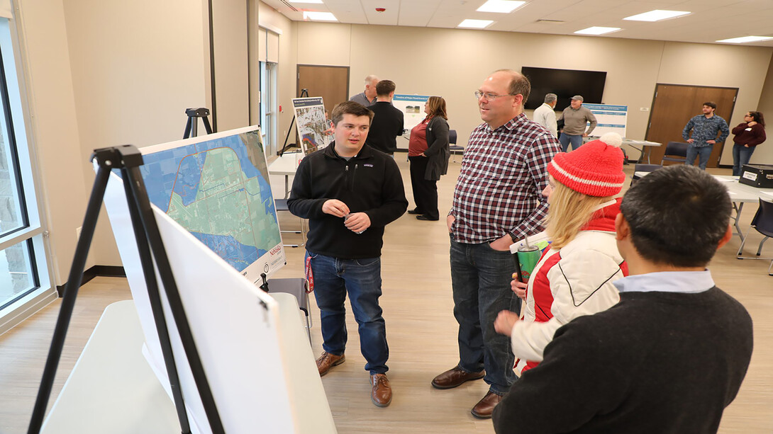 A student (left) discusses flooding mitigation with faculty (right) in front of flooding maps.